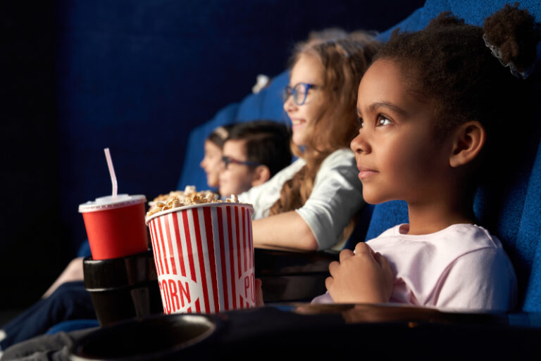 Niños viendo una película en el cine y comiendo palomitas